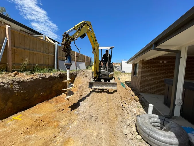 Mini excavator using an auger attachment for post hole drilling in Gippsland