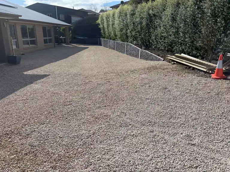 Crushed rock driveway finishing next to a new block retaining wall in Gippsland