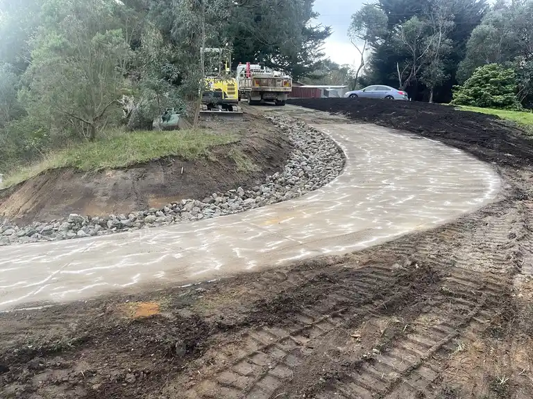 Finished curved concrete driveway with rock edging and earthworks
