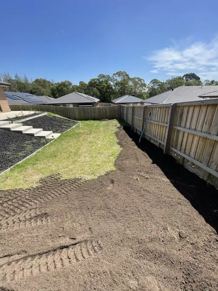 Soil leveling and earthworks along a residential fence line