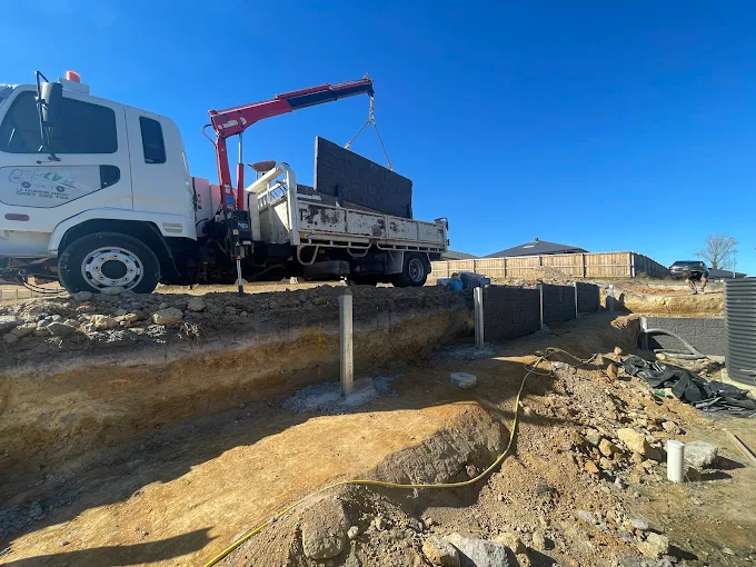 Crane truck installing heavy concrete sleepers for a retaining wall in Gippsland
