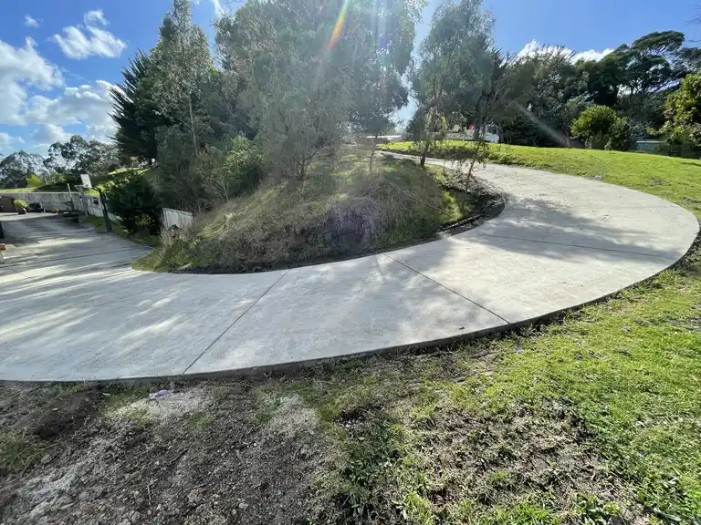 Sloped property earthworks and new curved concrete driveway installation