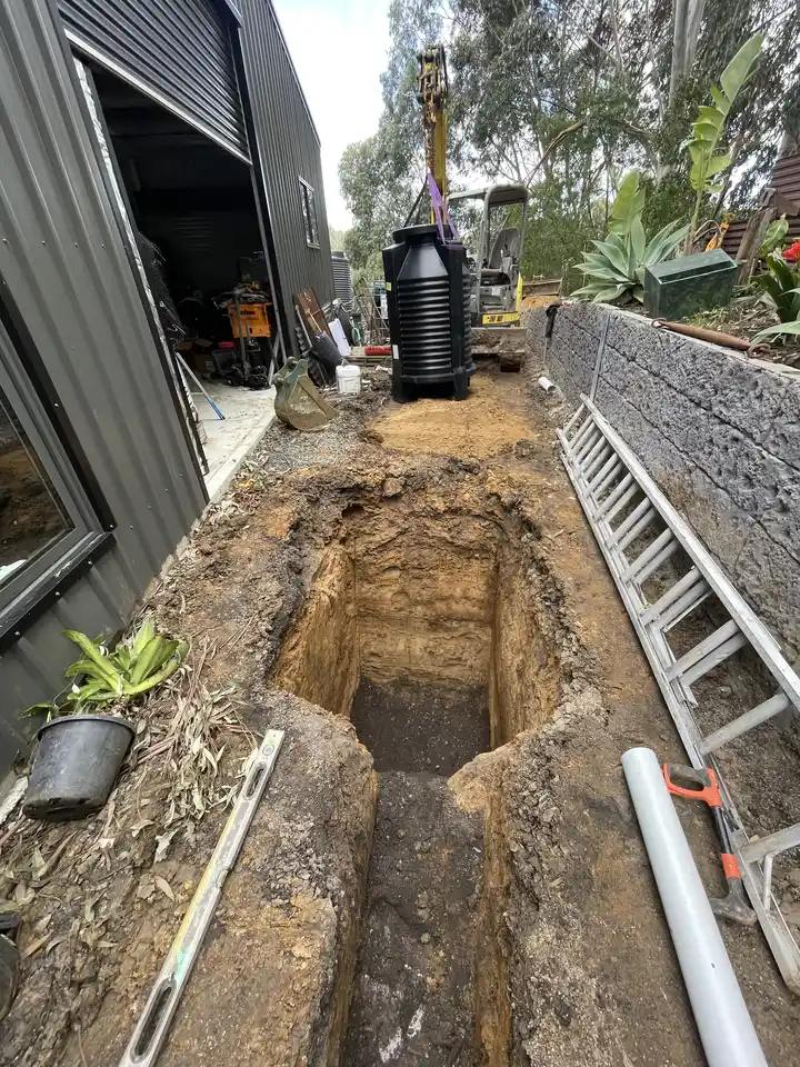 Underground tank installation and earthworks next to a block retaining wall